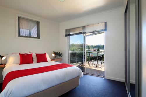a bedroom with a large bed and a balcony at Penguin Waterfront Escape in Penguin