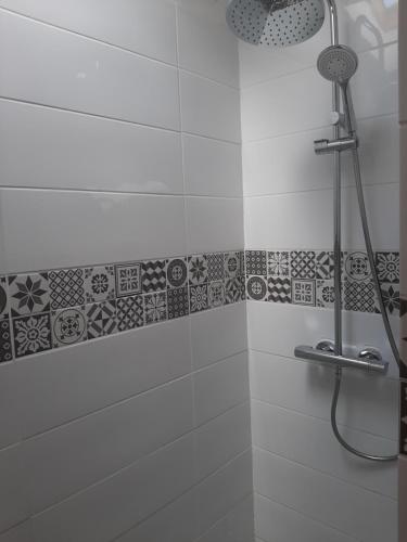 y baño con ducha y azulejos blancos y negros. en petite maison sympathique plein de charme, en Beychac-et-Caillau