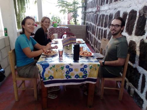 a group of people sitting at a table with food at Casa LLEMO in San Pedro La Laguna