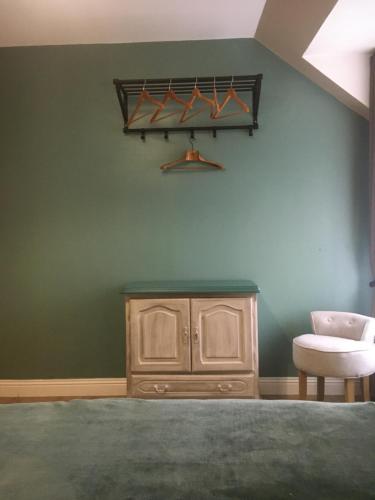 Cette chambre est dotée d'un mur vert avec une armoire et une chaise. dans l'établissement Appartement Les Remparts, à Boulogne-sur-Mer