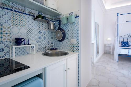 a small kitchen with a sink and blue and white tiles at Terrazza Zaffiro in Positano