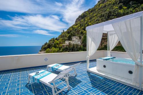 a balcony with a tub and chairs and the ocean at Terrazza Zaffiro in Positano