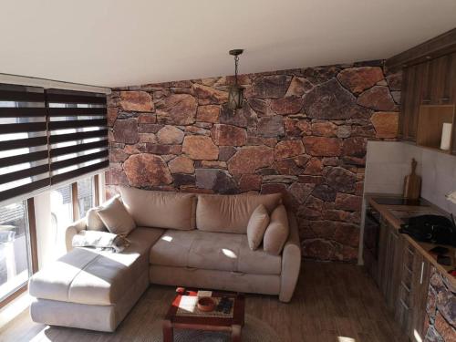 a living room with a couch and a stone wall at LAKI apartman in Zaovine