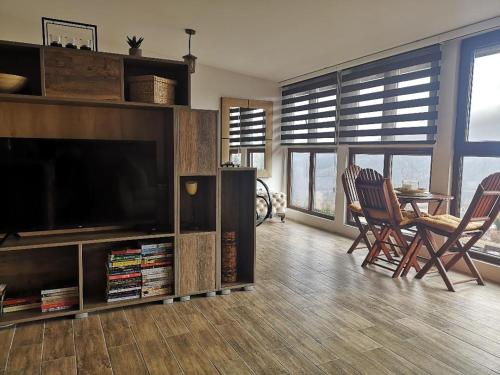 ein Wohnzimmer mit einem TV, einem Tisch und Stühlen in der Unterkunft LAKI apartman in Zaovine