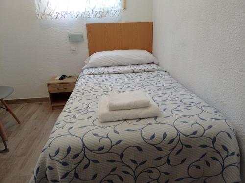 Pension Cuatro Torres في مدريد: سرير عليه منشفتين في غرفة