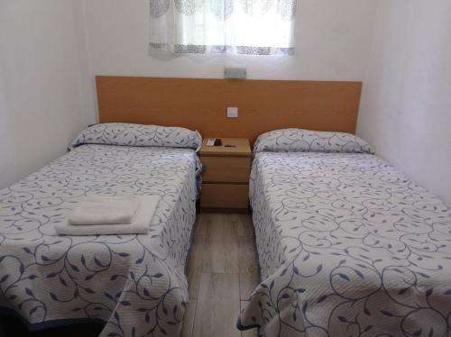 1 dormitorio con 2 camas y suelo de madera en Pension Cuatro Torres en Madrid