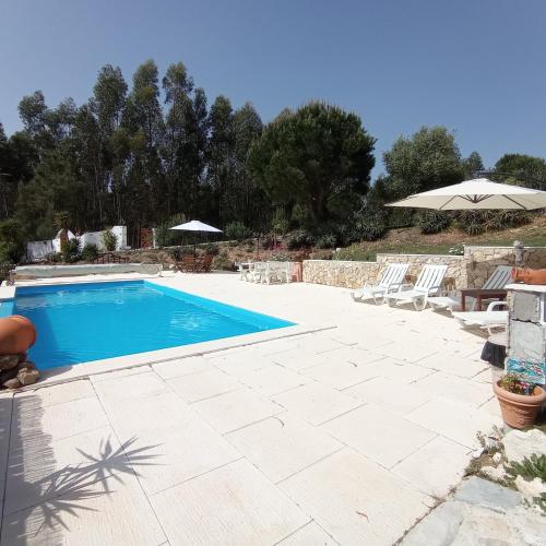 a swimming pool with chairs and an umbrella at Moinho da Amélia in Cadaval