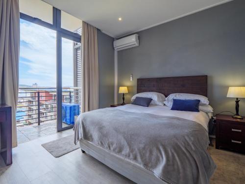Un dormitorio con una cama grande y una ventana grande. en Point Bay - Super Stylish for Less, en Durban