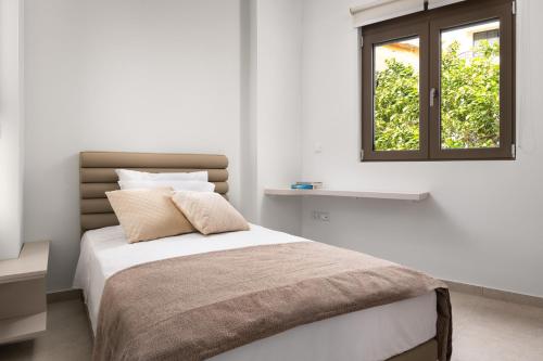 um quarto branco com uma cama e uma janela em Onirico House in Ilha de Rhodes