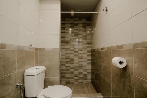 a bathroom with a toilet and a tiled wall at AIORA yard in Ammouliani