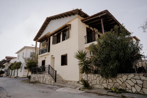 a white house with a stone wall at AIORA yard in Ammouliani