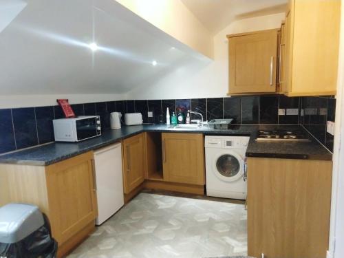 a kitchen with wooden cabinets and a washer and dryer at Derwent Street Apartment 3 - Self Contained - 2 Bed Self Catering Apartment in Workington