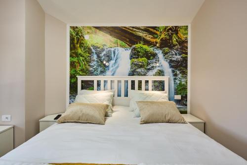 a bedroom with a white bed with a waterfall mural at AquaLux 2 in Soko Banja