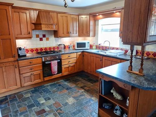 a kitchen with wooden cabinets and a stove top oven at Carnlough Cottage in Carnlough