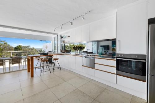 a kitchen with white cabinets and a table with chairs at Noosa Views Apartment 4 in Noosa Heads