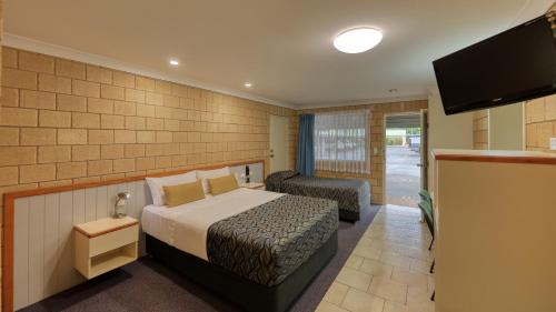 Habitación de hotel con cama y TV de pantalla plana. en Jacaranda Country Motel, en Saint George