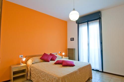 1 dormitorio con paredes de color naranja y 1 cama con almohadas rojas en Appartamenti CALDERONE en Rímini