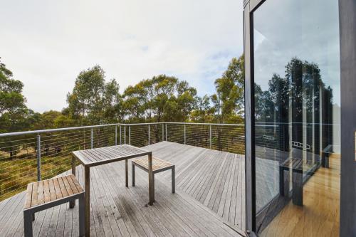 a balcony with a table and a bench on a deck at Denison Rivulet Retreats in Bicheno
