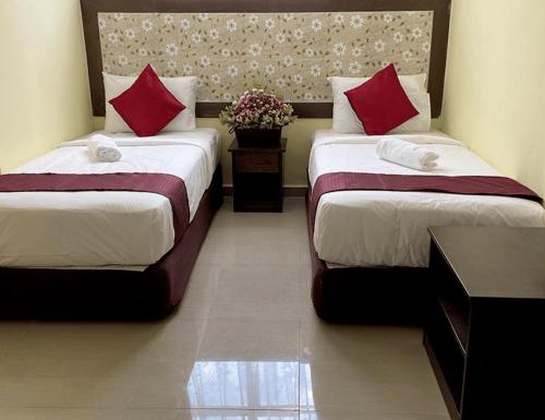 two beds in a hotel room with red pillows at Sun Inns Hotel Meru Raya in Chemor