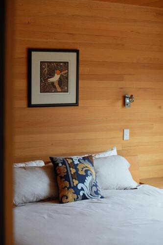 a bedroom with a bed with a picture on the wall at Denison Rivulet Retreats in Bicheno