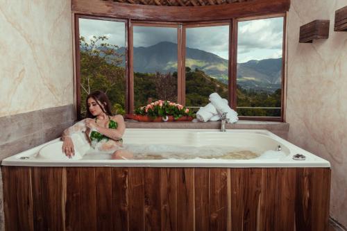 a woman sitting in a bath tub with a window at Hotel Campestre La Periquera in Villa de Leyva