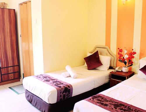 um quarto de hotel com duas camas e uma janela em Sun Inns Tambun em Kampong Batu Lapan