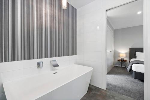 a white bathroom with a sink and a bedroom at River View Retreat - Taupo in Taupo