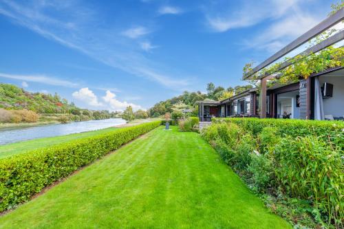 a house with a green lawn next to a river at River View Retreat - Taupo in Taupo