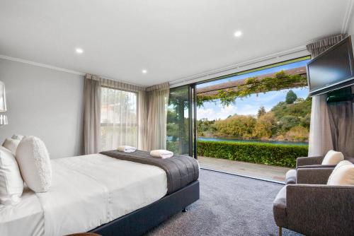 a bedroom with a bed and a large window at River View Retreat - Taupo in Taupo