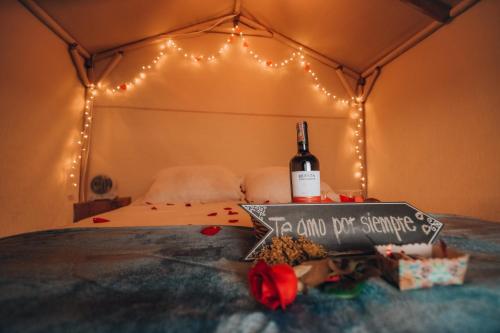 a bed with a bottle of wine and a sign on it at Glamping rio frio Tabio in Tabio