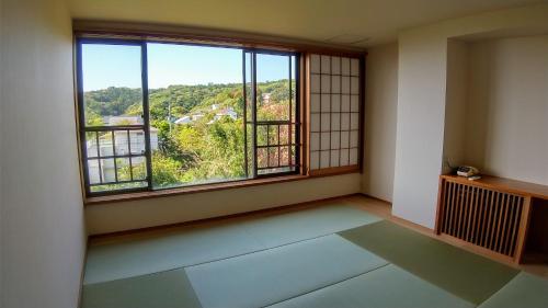 an empty room with a large window with a view at FUTO HOUSE -Ippon no Enpitsu- in Ito