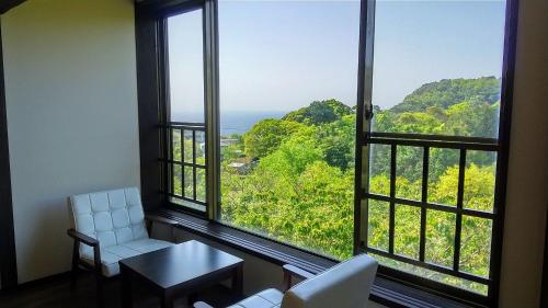 a room with a large window with a table and chairs at FUTO HOUSE -Ippon no Enpitsu- in Ito