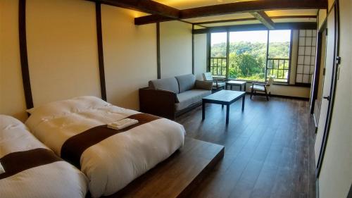 a room with two beds and a living room with a couch at FUTO HOUSE -Ippon no Enpitsu- in Ito