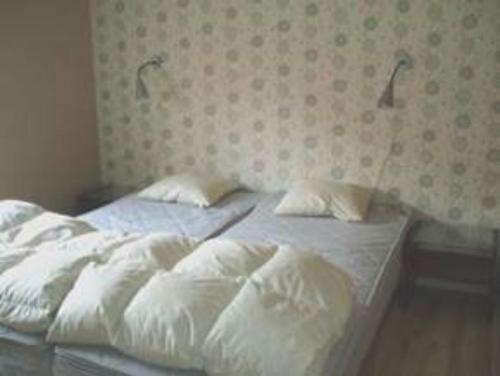a bed with white sheets and pillows in a bedroom at Lyckåhem Lågprishotell och Vandrarhem in Karlskrona