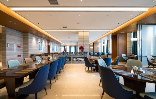 a restaurant with wooden tables and blue chairs at Shangrao International Hotel in Shangrao