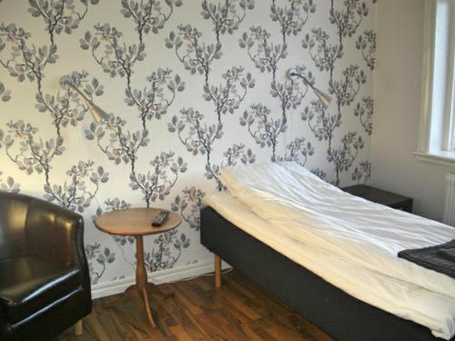 a bedroom with a bed and a table and wallpaper at Lyckåhem Lågprishotell och Vandrarhem in Karlskrona