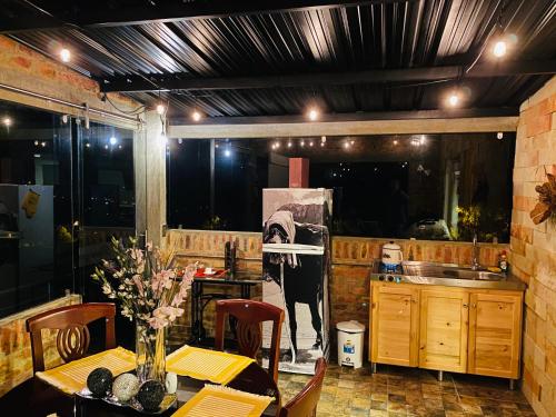 Romántica Cabaña con vista a la ciudad, 10 min del Centro في Chiquinquirá: مطبخ مع طاولة مع صورة بقرة