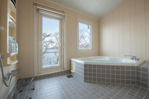 baño grande con bañera y 2 ventanas en Sea Side House Toya, en Lago Toya