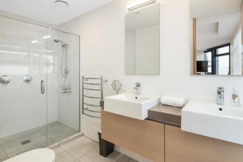 uma casa de banho branca com um lavatório e um chuveiro em Superb Elevated Views of Harbour with Heated Pool, Gym & Parking em Mount Maunganui