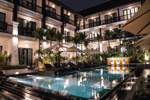 una piscina de hotel con sillas y sombrillas en Aksara Heritage -SHA Extra Plus en Chiang Mai