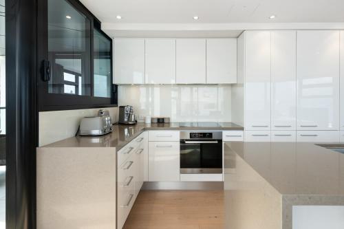 a kitchen with white cabinets and a counter top at Superb Elevated Views of Harbour with Heated Pool, Gym & Parking in Mount Maunganui