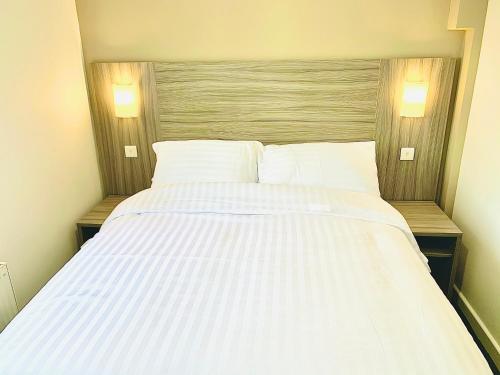 a large white bed in a room with two lamps at De Regency Style Hotel in Redditch