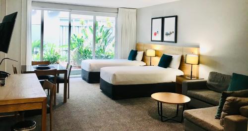 um quarto de hotel com duas camas e um sofá em Quest Brighton on the Bay em Melbourne