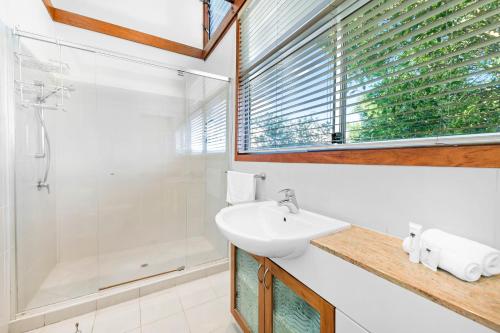 La salle de bains blanche est pourvue d'un lavabo et d'une douche. dans l'établissement Serenity - Mudjimba - Pet Friendly Holiday Home, à Mudjimba
