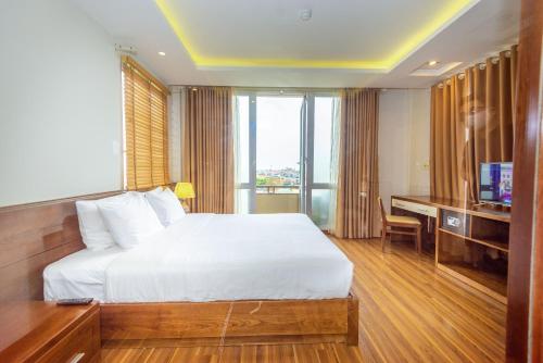 a bedroom with a bed and a desk with a television at Lotus Hotel Hai Duong in Hải Dương
