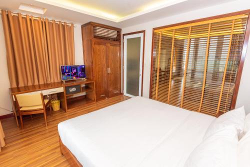 a bedroom with a bed and a desk and a television at Lotus Hotel Hai Duong in Hải Dương