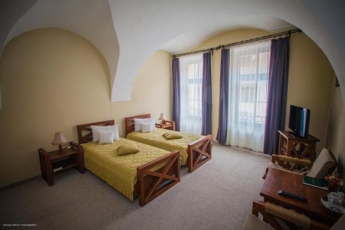 una camera d'albergo con due letti e una televisione di Hotel Sighişoara a Sighişoara