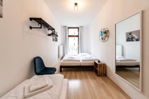 um quarto com um espelho, uma cadeira e 2 camas em Ko-Living - Apartment am Wasserturm - vintage & industrial em Halle an der Saale