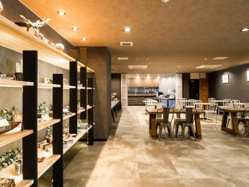 a restaurant with tables and chairs and a kitchen at Hotel Area One Ise Inter in Ise