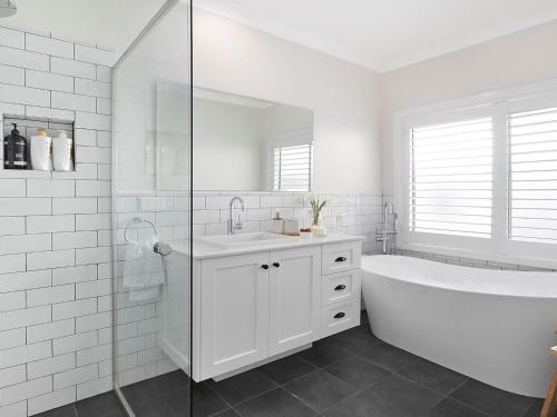 a white bathroom with a tub and a sink at Elm Cottage in Berry